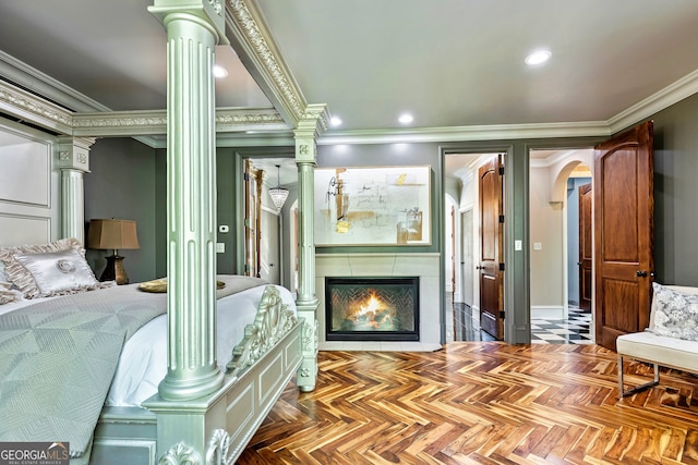 bedroom featuring a tile fireplace, crown molding, ornate columns, and parquet floors