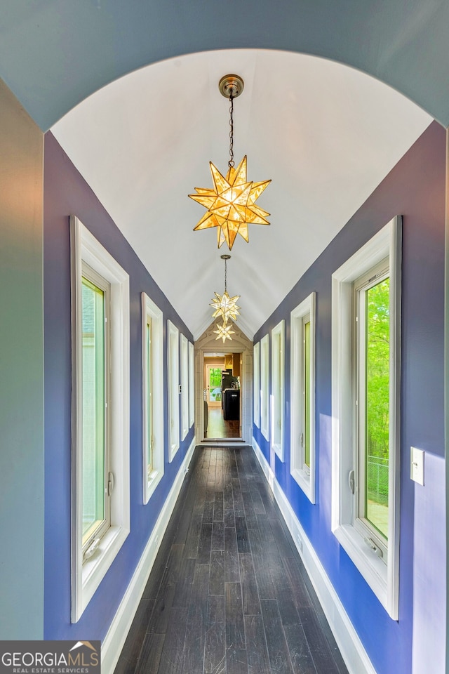 hall with a notable chandelier, vaulted ceiling, and dark hardwood / wood-style floors