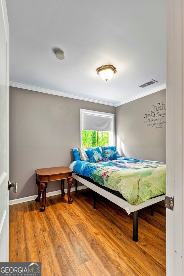 bedroom featuring ornamental molding and wood-type flooring