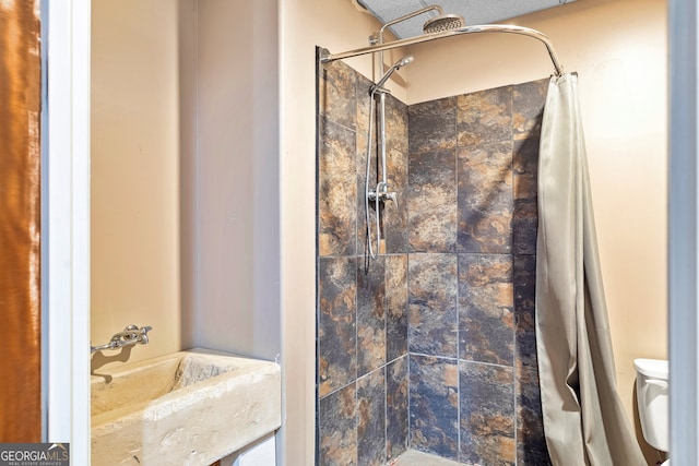 bathroom featuring sink, toilet, walk in shower, and a textured ceiling