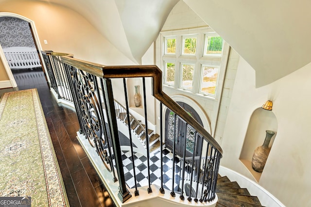 stairway with lofted ceiling and hardwood / wood-style floors