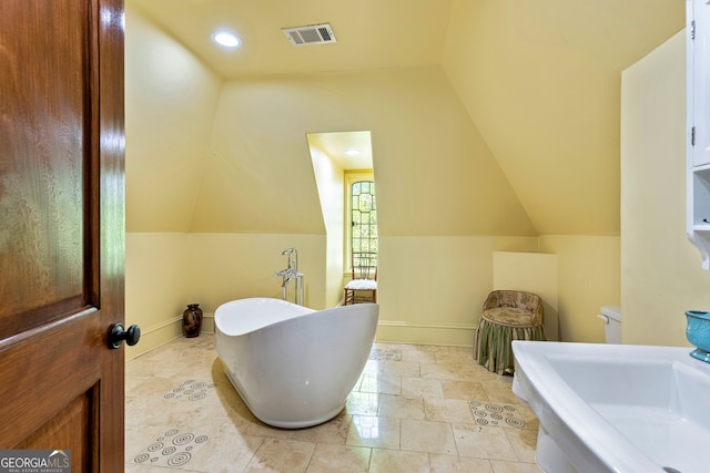 bathroom with vaulted ceiling and a washtub