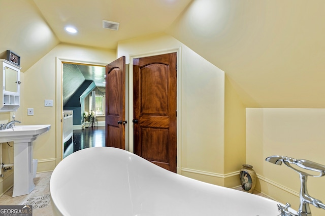 bathroom with sink, vaulted ceiling, and a bathing tub