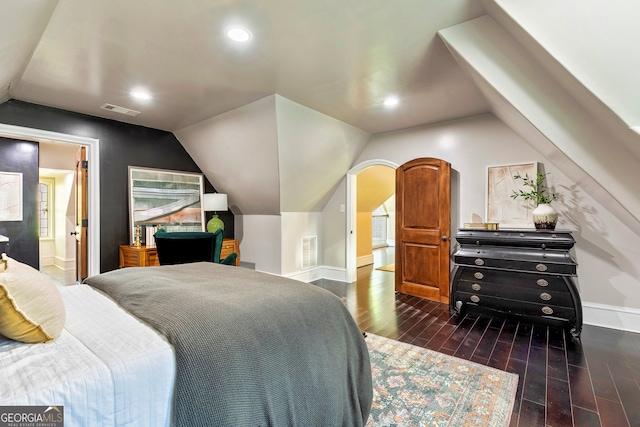 bedroom featuring ensuite bath, dark wood-type flooring, and vaulted ceiling