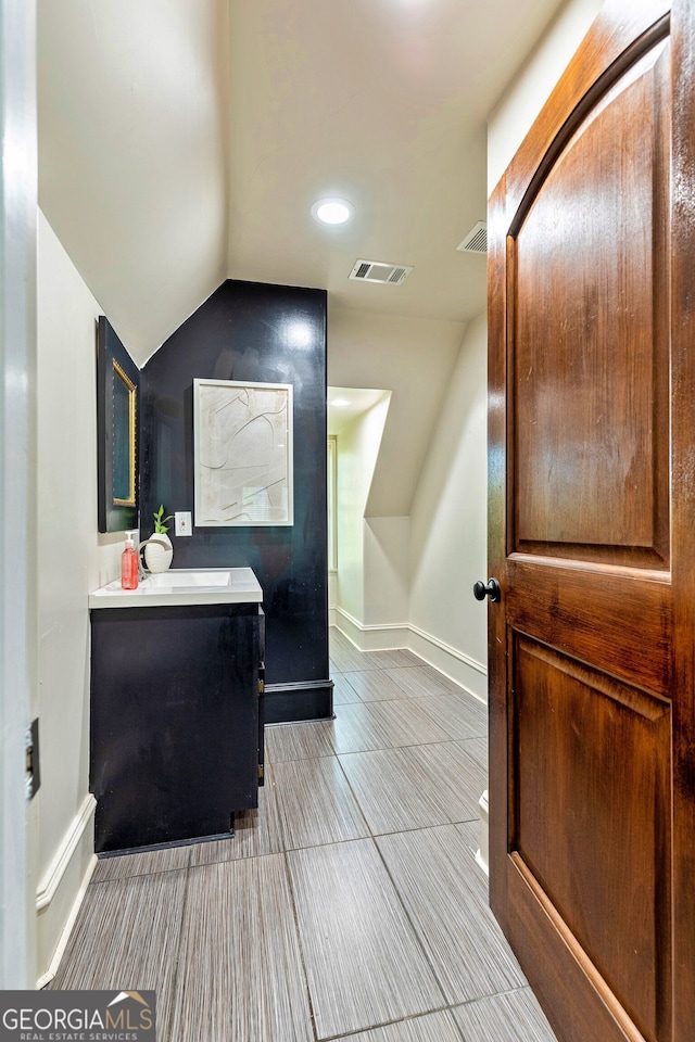 bathroom featuring vanity, tile patterned flooring, and vaulted ceiling