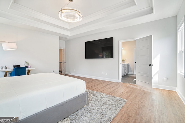 bedroom with a raised ceiling, a chandelier, hardwood / wood-style flooring, crown molding, and ensuite bathroom