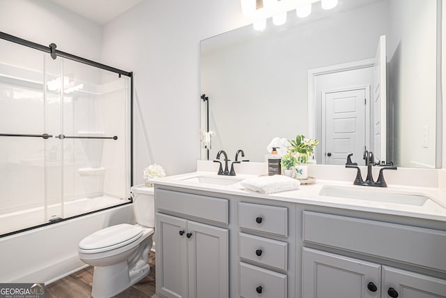 full bathroom featuring shower / bath combination with glass door, vanity, toilet, and wood-type flooring