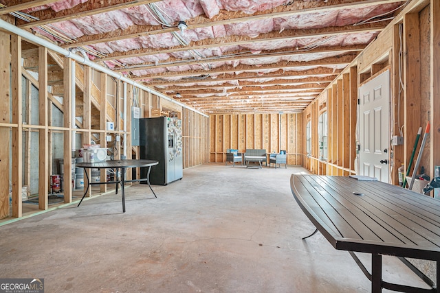 basement featuring electric panel and stainless steel fridge