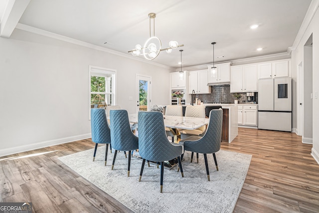 dining room with ornamental molding, a notable chandelier, and light hardwood / wood-style flooring