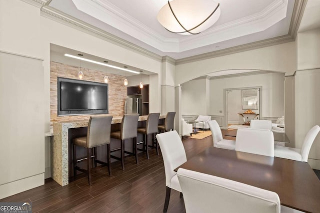 dining space featuring a tray ceiling, dark hardwood / wood-style floors, decorative columns, and crown molding