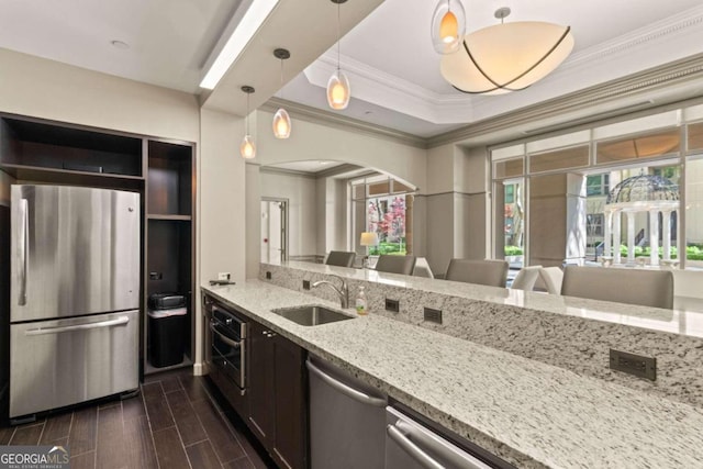 kitchen with light stone counters, pendant lighting, sink, appliances with stainless steel finishes, and dark hardwood / wood-style flooring