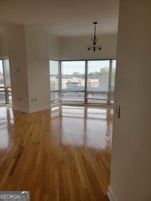 unfurnished room featuring a notable chandelier, crown molding, and light hardwood / wood-style flooring