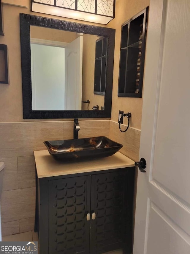 bathroom featuring vanity, tile walls, and toilet