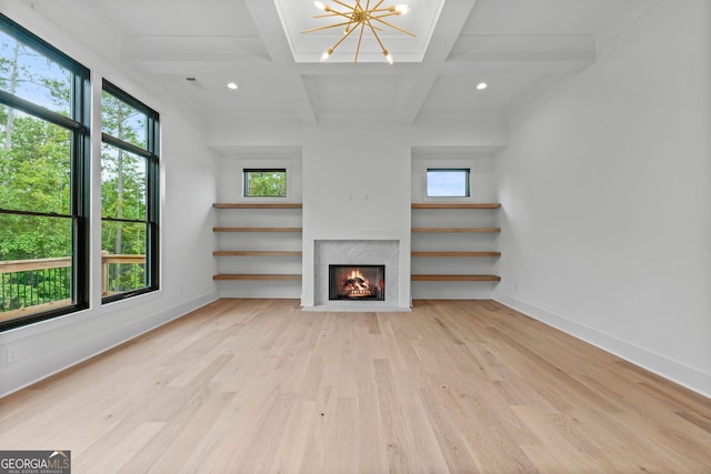 unfurnished living room with light hardwood / wood-style floors, a chandelier, beam ceiling, and coffered ceiling