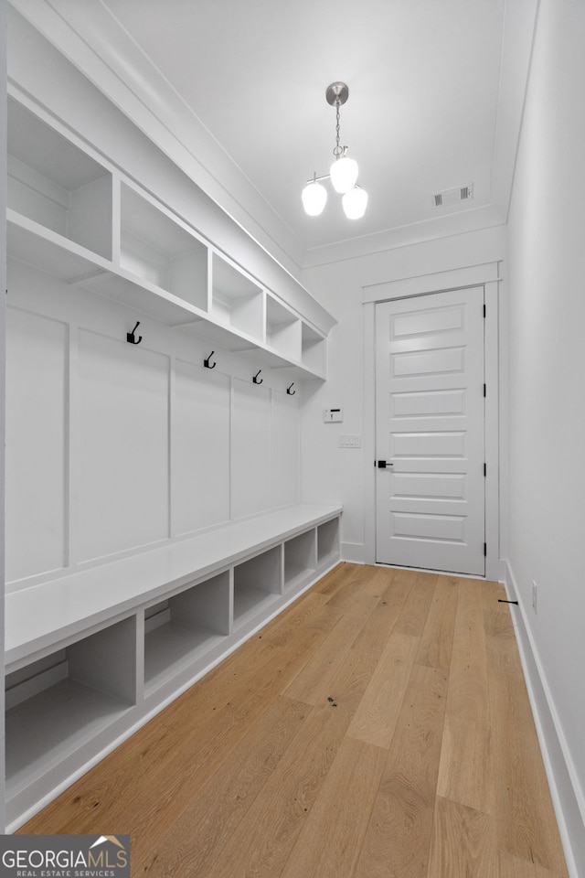 mudroom featuring crown molding, hardwood / wood-style floors, and a chandelier