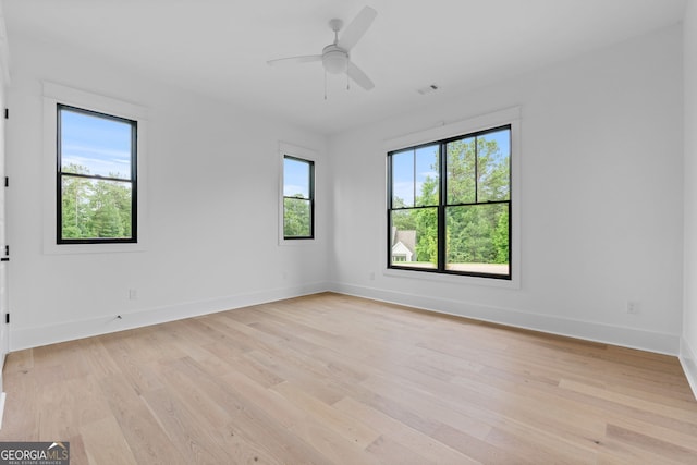 empty room with ceiling fan, light wood-type flooring, and a healthy amount of sunlight