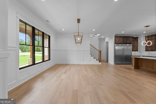 unfurnished living room with a notable chandelier and light wood-type flooring