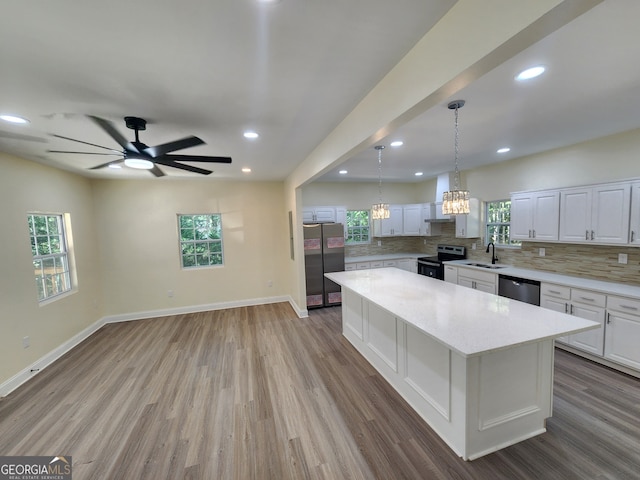 kitchen with stainless steel appliances, white cabinets, a center island, and a wealth of natural light