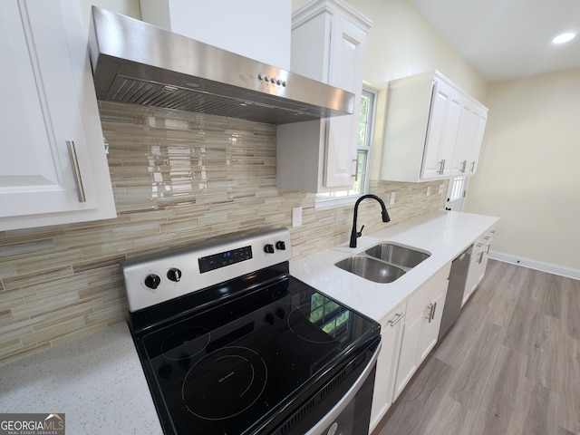 kitchen featuring black range with electric stovetop, white cabinets, sink, wall chimney range hood, and decorative backsplash