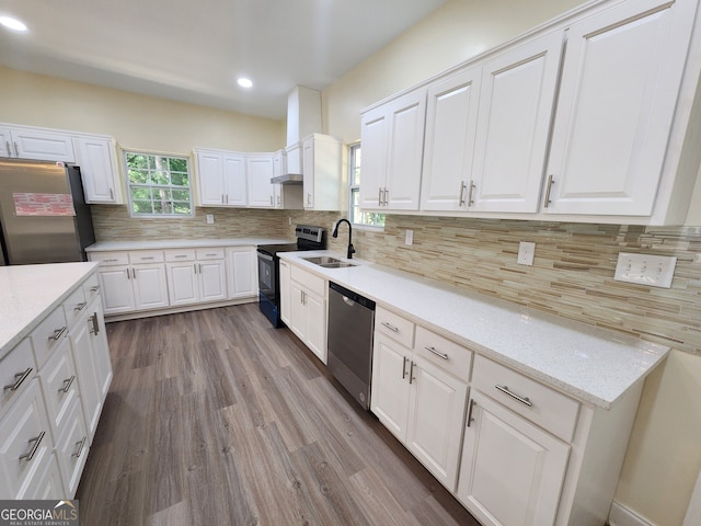 kitchen with appliances with stainless steel finishes, white cabinetry, hardwood / wood-style floors, and backsplash