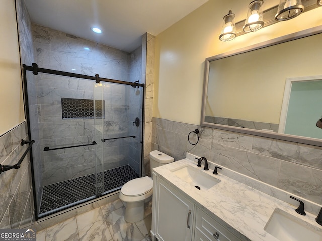 bathroom with vanity, tile walls, toilet, and a shower with shower door