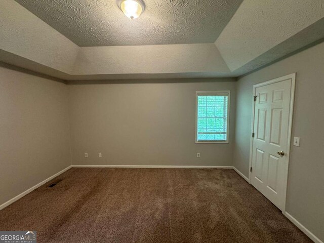 unfurnished bedroom with carpet floors, a textured ceiling, and a tray ceiling