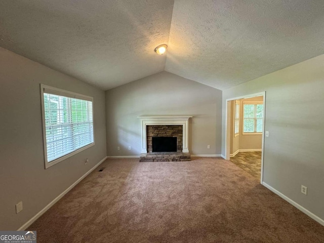 unfurnished living room featuring a fireplace, carpet floors, vaulted ceiling, and a textured ceiling