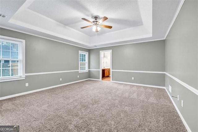 carpeted empty room with ceiling fan and a raised ceiling