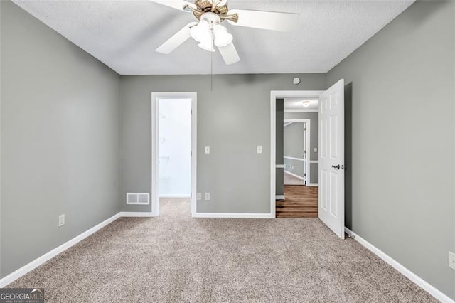 unfurnished bedroom with ceiling fan, light colored carpet, and a textured ceiling