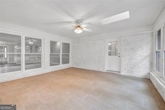 unfurnished sunroom with ceiling fan and a skylight