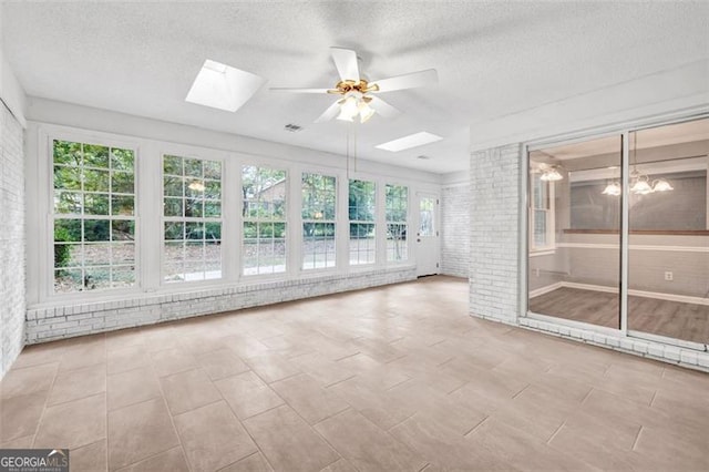 unfurnished sunroom with ceiling fan, a skylight, and a healthy amount of sunlight