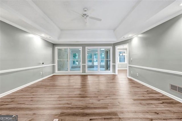 unfurnished living room featuring ceiling fan, light hardwood / wood-style flooring, crown molding, and a tray ceiling