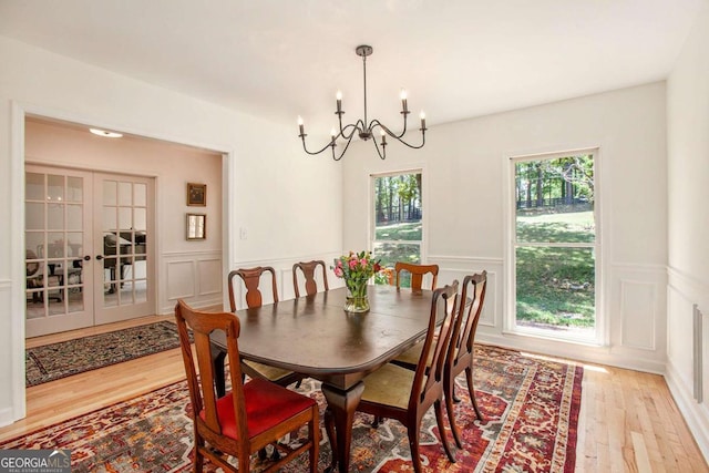 dining space with french doors, light hardwood / wood-style flooring, and a chandelier