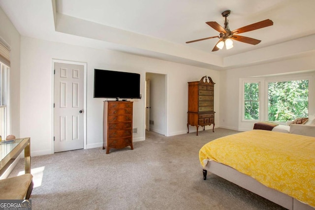 bedroom featuring light carpet, ceiling fan, and a raised ceiling