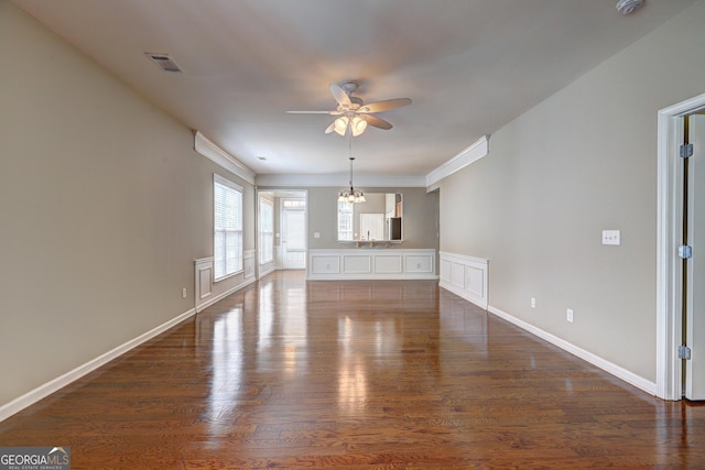 unfurnished living room featuring ceiling fan with notable chandelier, dark hardwood / wood-style flooring, and crown molding