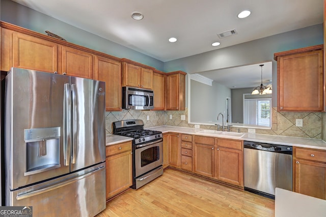 kitchen with backsplash, sink, stainless steel appliances, and a chandelier