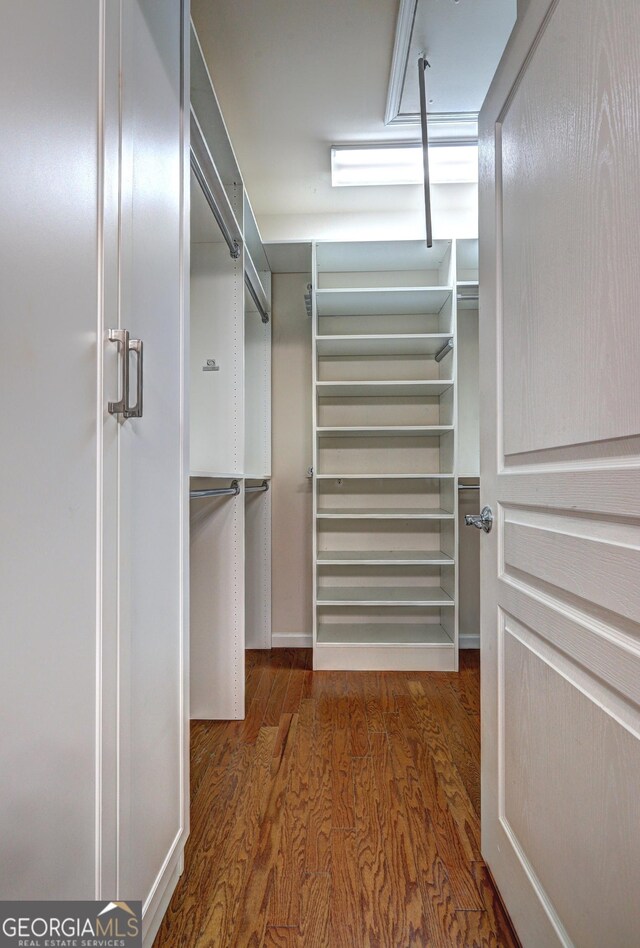 walk in closet with dark hardwood / wood-style floors