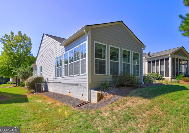 view of side of property with a sunroom, cooling unit, and a yard