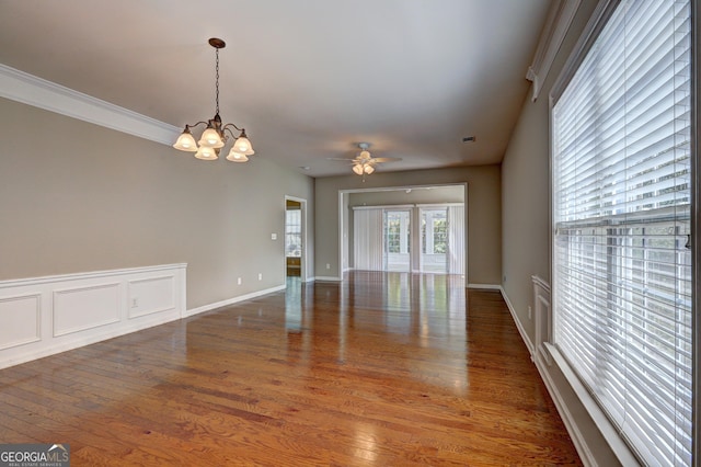 spare room with ceiling fan with notable chandelier, dark hardwood / wood-style flooring, and ornamental molding