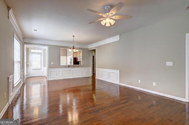 unfurnished room with dark hardwood / wood-style floors, ceiling fan with notable chandelier, and ornamental molding