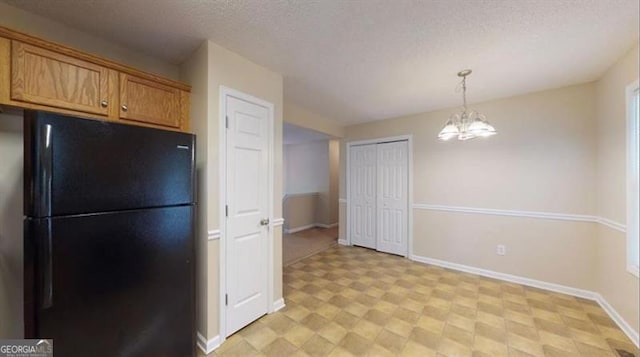 kitchen with black fridge, pendant lighting, a chandelier, and a textured ceiling