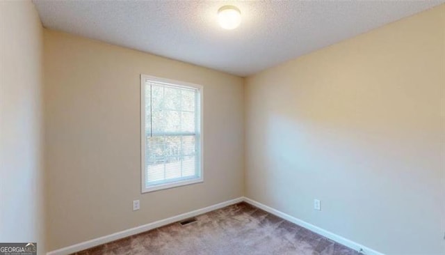 carpeted spare room with a textured ceiling