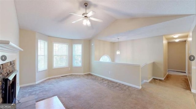 unfurnished living room featuring lofted ceiling, a fireplace, ceiling fan, and light colored carpet