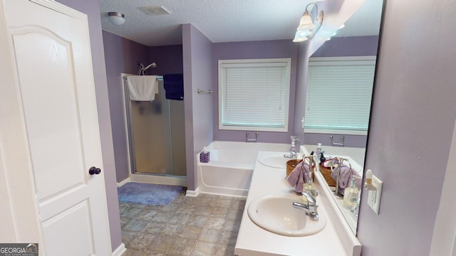 bathroom featuring separate shower and tub, vanity, and a textured ceiling