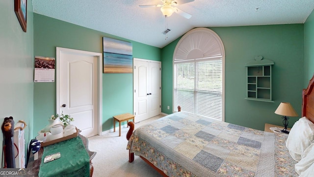 carpeted bedroom with ceiling fan, a textured ceiling, a closet, and vaulted ceiling