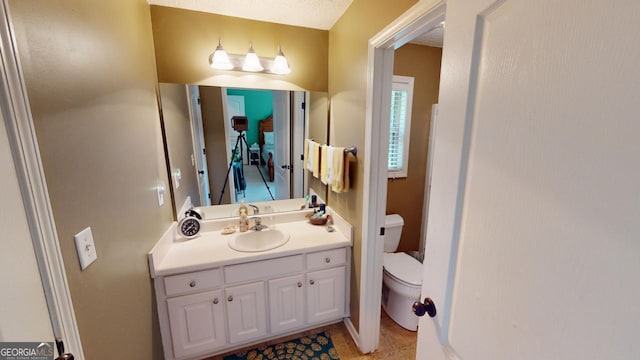 bathroom featuring a textured ceiling, vanity, and toilet