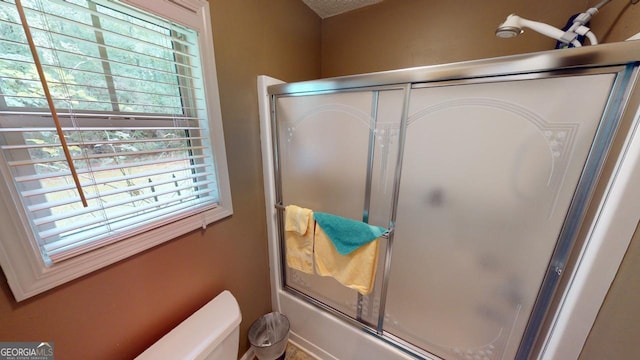 bathroom with shower / bath combination with glass door and toilet