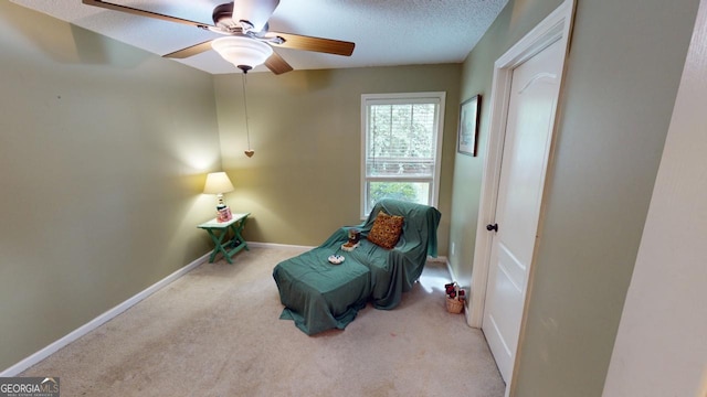 sitting room featuring light carpet, ceiling fan, and a textured ceiling