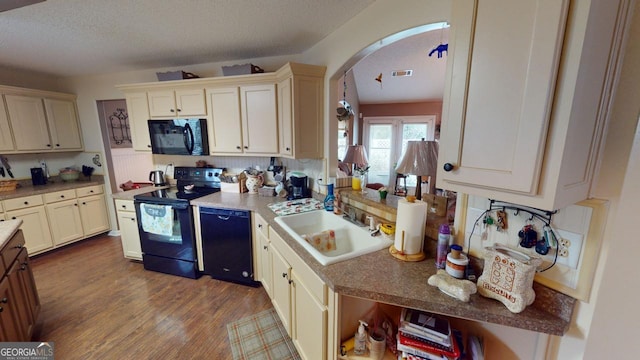 kitchen featuring black appliances, sink, cream cabinetry, light hardwood / wood-style flooring, and a textured ceiling