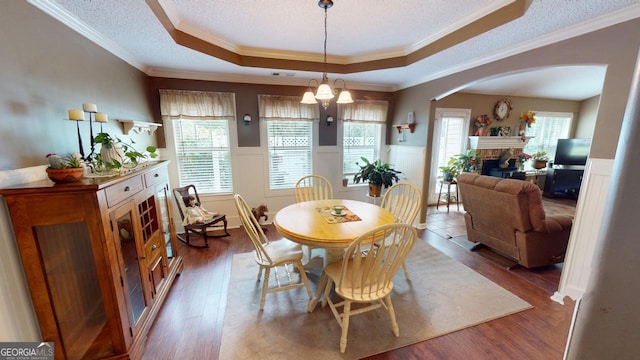 dining area featuring an inviting chandelier, crown molding, a tray ceiling, a fireplace, and hardwood / wood-style flooring